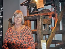 Kvinna framför en stor äldre textilmaskin på Textilmuseet