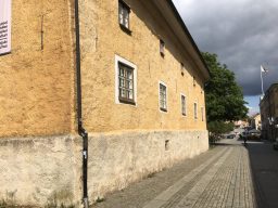 Lång tvåvåningsbyggnad i gult puts längs en kullerstenstrottoar i Alingsås